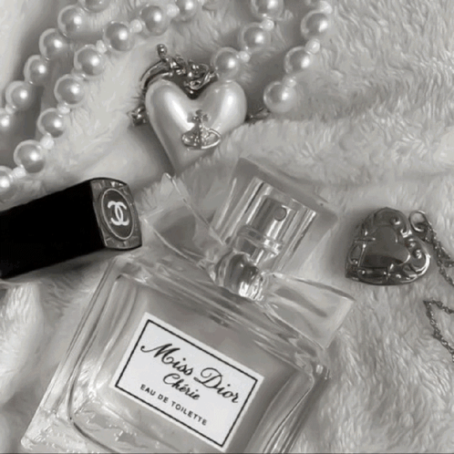 A Bottle Of Miss Dior Cherie Eau De Toilette Next To A Chanel Lipstick And Pearls GIF