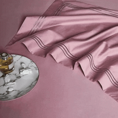 A Bottle Of Perfume Sits On A Marble Tray Next To A Pink Sheet . GIF