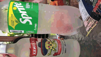 A Bottle Of Sprite Sits Next To A Bottle Of Kamikaze Tamarind Sprit GIF