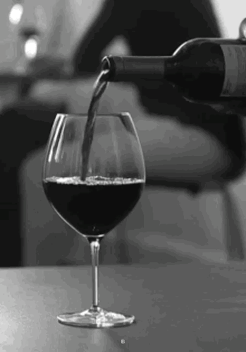 A Bottle Of Wine Is Being Poured Into A Glass Of Wine . GIF