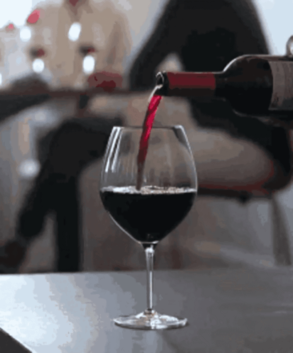A Bottle Of Wine Is Poured Into A Glass GIF