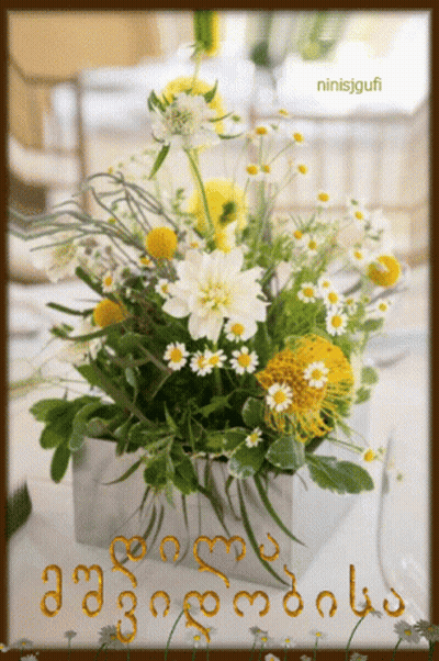 A Bouquet Of Yellow And White Daisies In A Silver Vase With The Name Ninisjgufi On The Bottom GIF