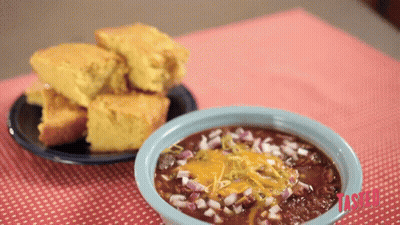 A Bowl Of Chili Sits On A Table Next To A Bowl Of Cornbread GIF