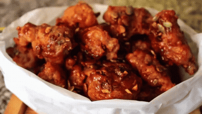 A Bowl Of Fried Chicken Covered In Sauce GIF