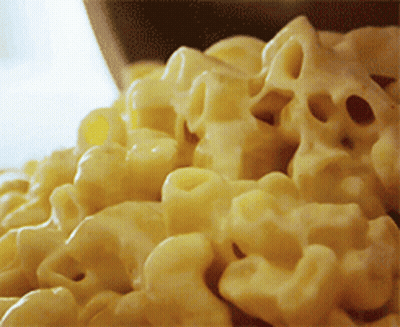 A Bowl Of Macaroni And Cheese Is Being Poured Into A Bowl GIF