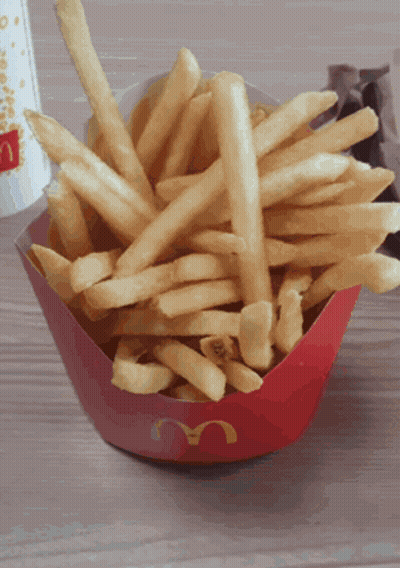 A Bowl Of Mcdonald 'S French Fries Sits On A Wooden Table GIF