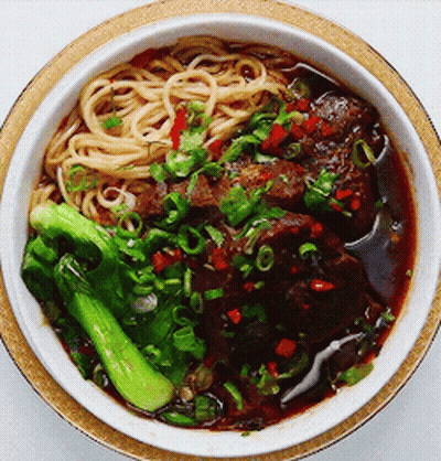 A Bowl Of Noodles With Meat And Broccoli In It GIF