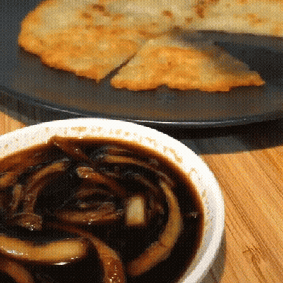 A Bowl Of Sauce Next To A Plate Of Food On A Table GIF