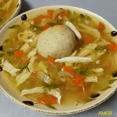A Bowl Of Soup With Chicken Carrots And A Matzo Ball In It GIF