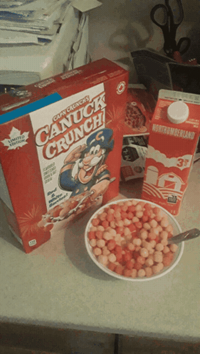 a box of canuck crunch cereal next to a bowl of cereal and a carton of milk