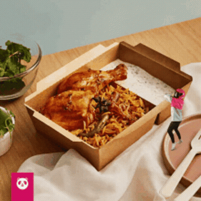 A Box Of Food With Chicken And Rice On A Table With A Panda Logo In The Corner GIF