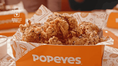 A Box Of Fried Chicken From Popeyes Is On A Table GIF