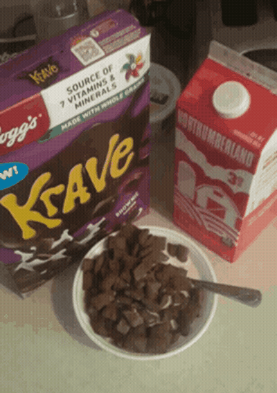 A Box Of Krave Cereal Sits Next To A Bowl Of Cereal And A Carton Of Milk GIF