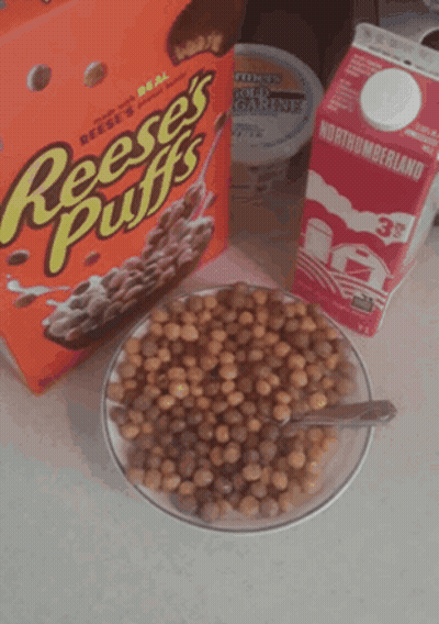 A Box Of Reese 'S Puffs Cereal Next To A Bowl Of Cereal And A Carton Of Milk GIF