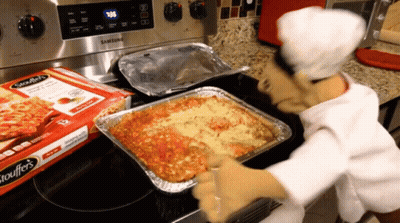 A Box Of Spaghettios Sits On A Stove Next To A Tray Of Lasagna GIF