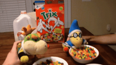 A Box Of Trix Cereal Sits On A Table Next To Two Stuffed Animals GIF