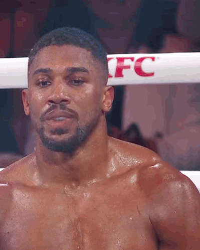 A Boxer Without A Shirt Is Standing In A Boxing Ring . GIF