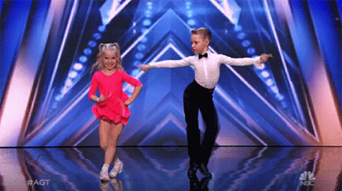 A Boy And A Girl Are Dancing On A Stage With A Nbc Logo In The Background . GIF