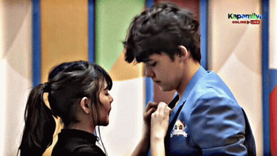 A Boy And A Girl Are Kissing In Front Of A Sign That Says Kapaliya GIF