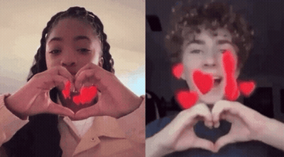 A Boy And A Girl Are Making A Heart Shape With Their Hands GIF