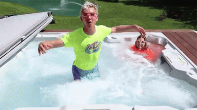 A Boy And A Girl Are Playing In A Hot Tub . The Boy Is Wearing A Neon Green Shirt . GIF