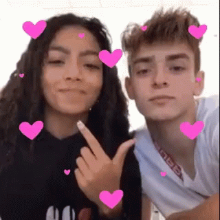 A Boy And A Girl Are Posing For A Picture With Pink Hearts Around Them . GIF