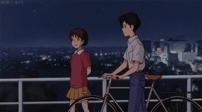 A Boy And A Girl Are Standing Next To A Bicycle On A Balcony Overlooking A City At Night . GIF
