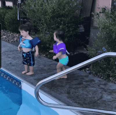 A Boy And A Girl Are Standing Next To A Pool Wearing Life Jackets GIF