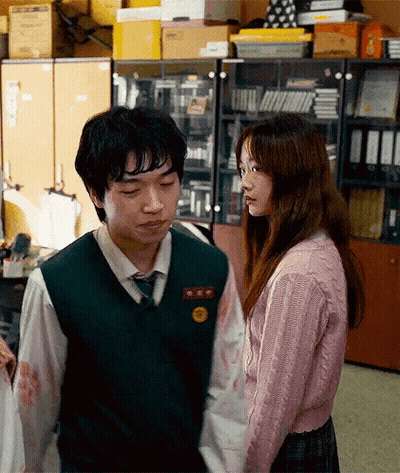 A Boy And A Girl Are Standing Next To Each Other In A Room Holding Hands . GIF