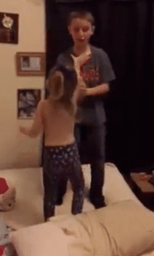 A Boy And A Girl Are Standing On A Bed GIF