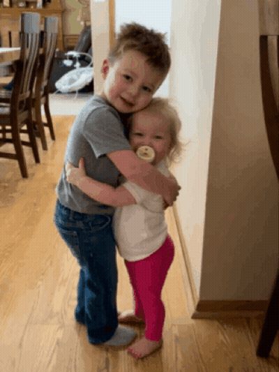 A Boy And A Girl Hugging Each Other In A Room GIF