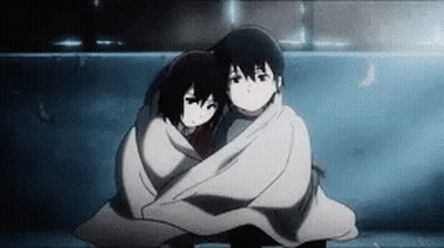 A Boy And A Girl Wrapped In A Blanket Are Hugging Each Other . GIF