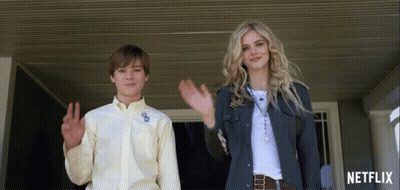 A Boy And A Woman Are Waving In Front Of A Netflix Ad GIF
