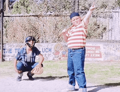 A Boy Holding A Bat Stands In Front Of A Sign That Says Next GIF