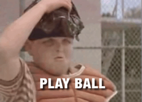 A Boy In A Baseball Uniform Is Holding His Helmet And Says Play Ball GIF