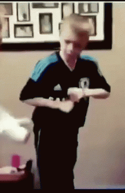 A Boy In A Black And Blue Adidas Shirt Is Holding A Wii Controller GIF