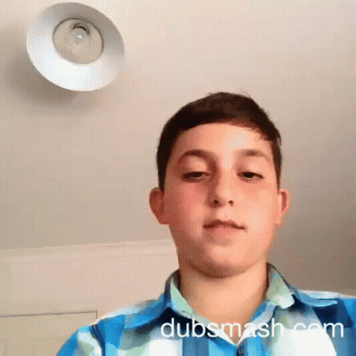 A Boy In A Blue And White Plaid Shirt Looks At The Camera With Dubsmash.com Written On The Bottom Right GIF