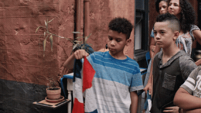A Boy In A Blue And White Shirt Is Holding A Red White And Blue Flag GIF