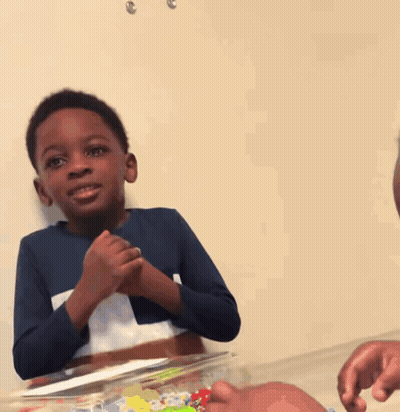 A Boy In A Blue Shirt Is Clapping His Hands In Front Of A Cake GIF