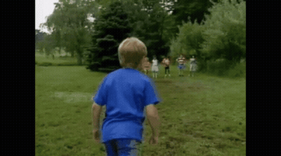 A Boy In A Blue Shirt Is Running In A Grassy Field GIF