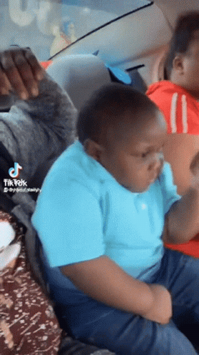 A Boy In A Blue Shirt Is Sitting In The Back Seat Of A Car With A Tik Tok Watermark GIF