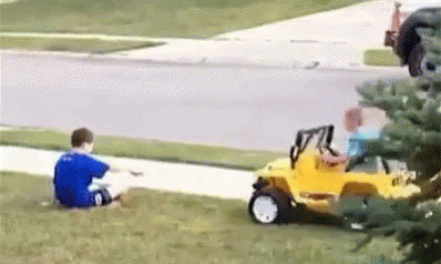 A Boy In A Blue Shirt Is Sitting On The Grass Next To A Yellow Toy Car . GIF