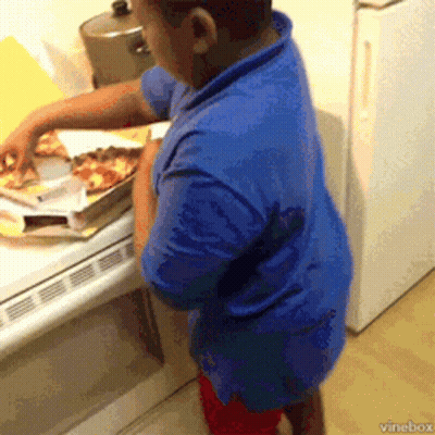 A Boy In A Blue Shirt Is Taking A Slice Of Pizza From A Box GIF