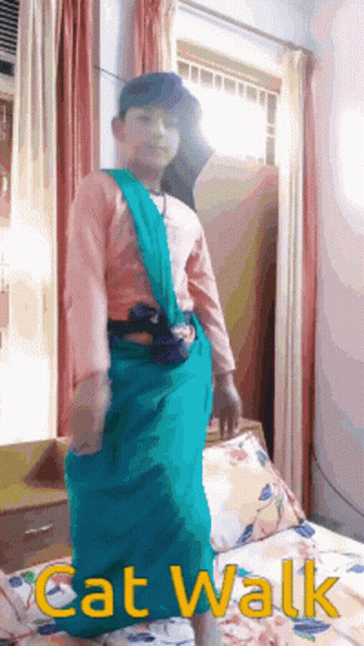 A Boy In A Cat Walk Costume Is Standing In Front Of A Window GIF