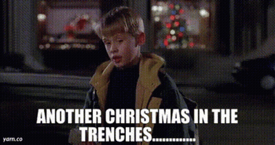 A Boy In A Jacket Is Standing In Front Of A Christmas Tree And Says Another Christmas In The Trenches . GIF