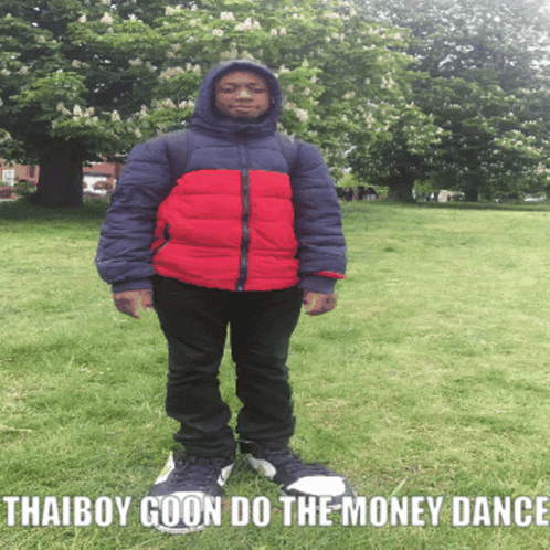 A Boy In A Red And Blue Jacket Is Standing In A Grassy Field With The Words Thaiboy Goon Do The Money Dance Below Him GIF