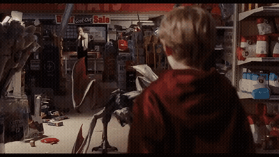 A Boy In A Red Hoodie Stands In Front Of A Store With A Sign That Says Bargains On It GIF