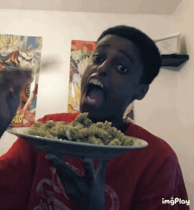A Boy In A Red Shirt Is Holding A Plate Of Pasta In His Hand GIF