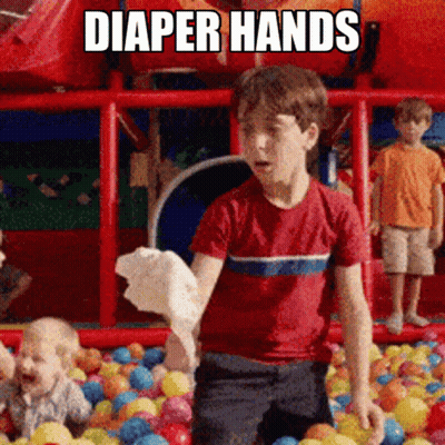 A Boy In A Red Shirt Is Standing In A Ball Pit With Diaper Hands Written On The Bottom GIF