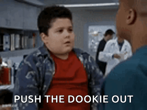 A Boy In A Red Shirt Is Talking To A Man In A Lab And The Words Push The Dookie Out Are Visible . GIF